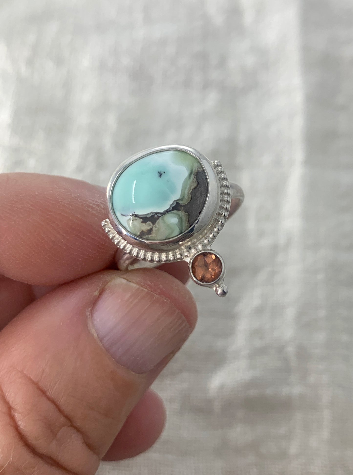 Hand fabricated, two stone, moderate statement ring featuring a stunning Poseidon Variscite cabochon paired with a bright, faceted pink/peach Tourmaline and silver raindrop and beaded wire details.