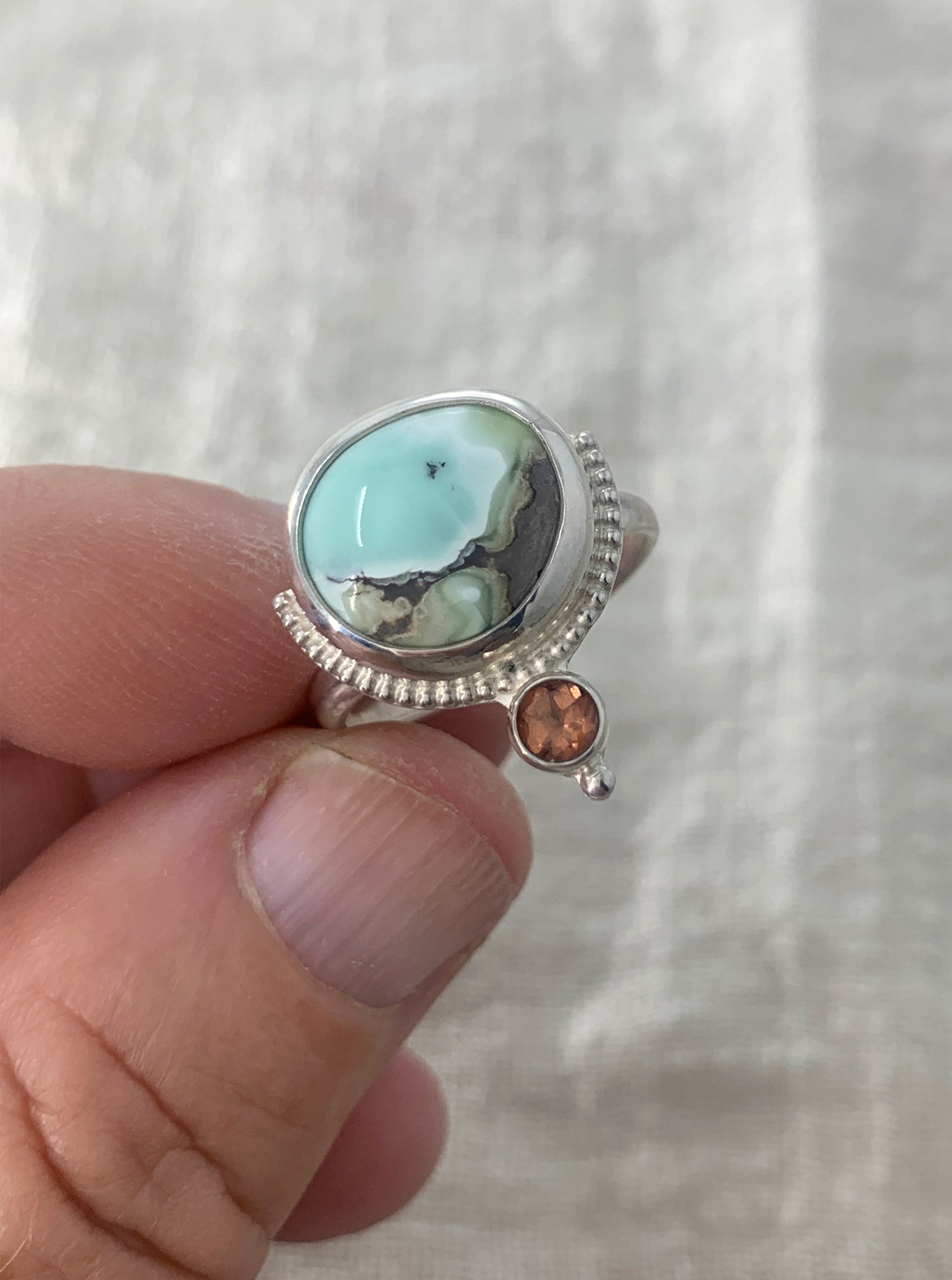 Hand fabricated, two stone, moderate statement ring featuring a stunning Poseidon Variscite cabochon paired with a bright, faceted pink/peach Tourmaline and silver raindrop and beaded wire details.