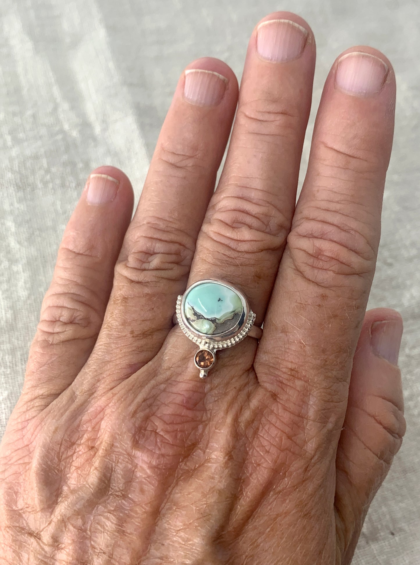 Hand fabricated, two stone, moderate statement ring featuring a stunning Poseidon Variscite cabochon paired with a bright, faceted pink/peach Tourmaline and silver raindrop and beaded wire details.